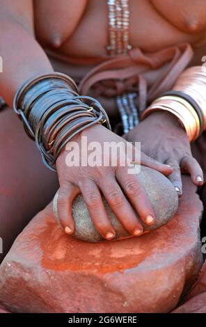 NAMIBIA. HIMBA DONNA CHE PREPARA IL ROSSO TRADIZIONALE OIGNMENT (OTJIRE) CHE USA PER PROTEGGERE LA SUA PELLE DAL SOLE, L'ARIA SECCA E GLI INSETTI. QUESTO OIG Foto Stock