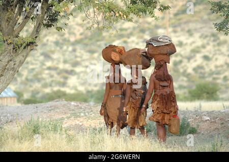 NAMIBIA. LE DONNE HIMBAS VANNO SPESSO PER LUNGHI VIAGGI CON IL MINIMO SULLA TESTA, UNA LIBERTÀ SPECIFICA DI QUESTO POPOLO. Foto Stock