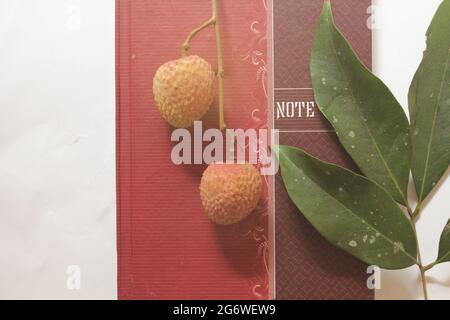 Frutta di litchi su libro di note, vista dall'alto Foto Stock