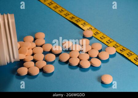 Contenitore per pill versato con nastro di misurazione su blu Foto Stock