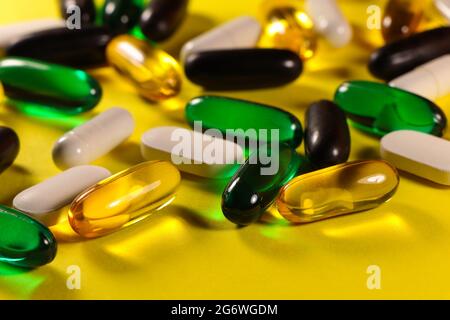 Varietà di pillole e capsule su superficie giallo brillante Foto Stock