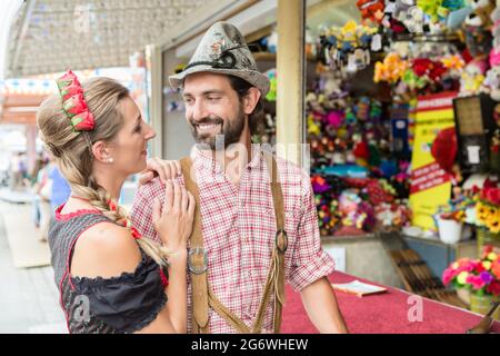 Uomo in Bavarian Tracht divertirsi in una galleria di tiro in fiera locale Foto Stock