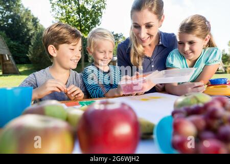 La mamma di pittura con le foto dei loro bambini e durante la pausa pranzo Foto Stock