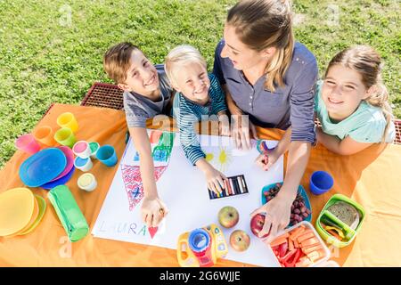 Scolare e scolari pittura durante la pausa pranzo con frutti e sandwich Foto Stock