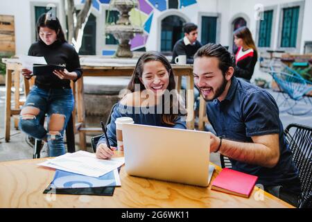 Felici giovani studenti messicani che lavorano insieme su un computer portatile in america latina Foto Stock