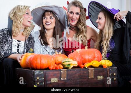 Tre giovani e belle donne che indossano divertente festa costumi mentre agiscono come le streghe, unendo le loro forze dannoso di Halloween Foto Stock