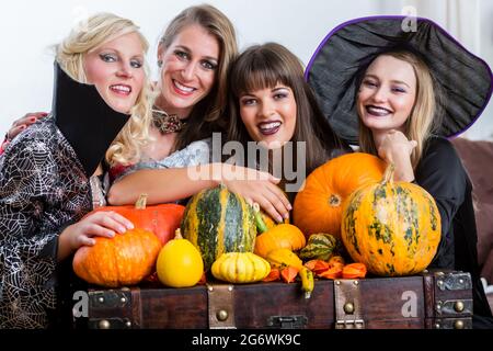 Quattro allegro belle donne durante la tostatura celebrare Halloween insieme durante la festa in costume al chiuso in una sala decorata Foto Stock