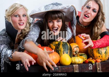 Quattro allegro belle donne durante la tostatura celebrare Halloween insieme durante la festa in costume al chiuso in una sala decorata Foto Stock