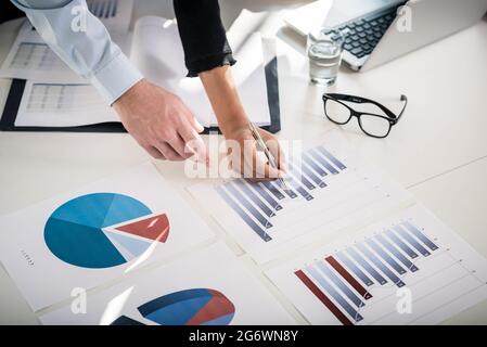 Gli esperti di Business analizzando le informazioni statistiche da verticale i grafici a torta e a barre stampato in ufficio Foto Stock