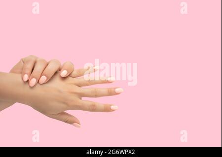 Belle mani femminili con elegante gel di manicure per unghie su sfondo rosa. Vista dall'alto delle mani femminili curate con manicure pastello su sfondo rosa Foto Stock