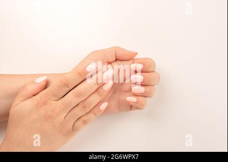Vista in primo piano della donna con belle mani su sfondo bianco, spazio per il testo. Trattamento spa. Vista dall'alto delle mani femminili curate con manicure pastello o Foto Stock