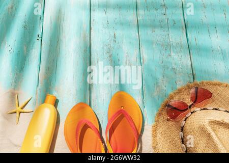 Accessori per il tempo libero e sabbia da spiaggia su uno sfondo di legno blu chiaro con spazio di copia in cima e ombra da una foglia di palma Foto Stock