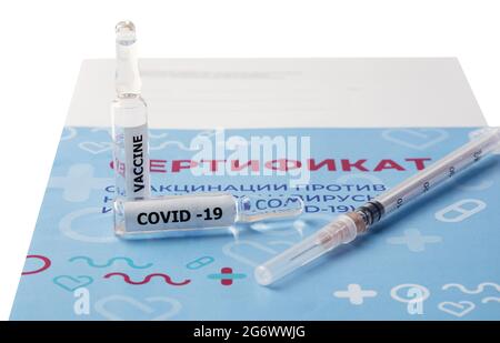 La siringa e le due fiale con il vaccino sono sul certificato di vaccinazione. Traduzione: Certificato di vaccinazione contro un nuovo coronavirus in Foto Stock