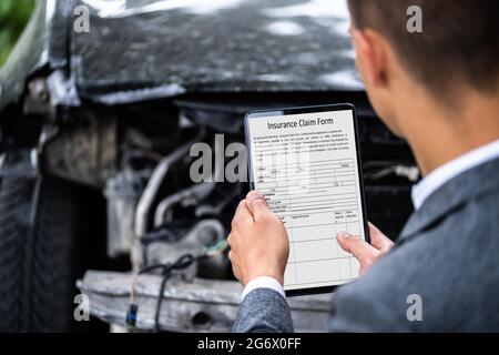 Agente assicurativo che ispetta l'automobile danneggiata con il tablet digitale Foto Stock