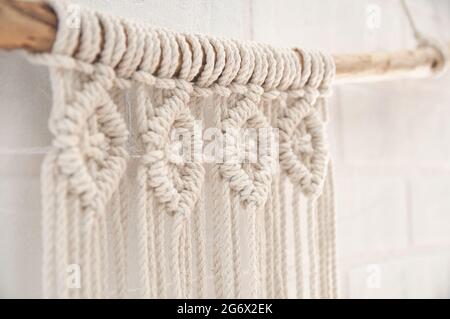 Murale boho murale fatto di fili di cotone di colore naturale usando la tecnica del macrame per l'arredamento domestico e di nozze Foto Stock