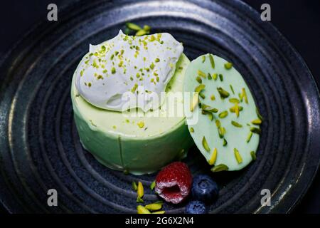 cheesecake dal sapore pistacchio, decorato con frutti di bosco e crema fresca Foto Stock