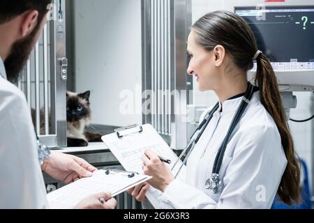 Medici veterinari in visita rotonda in UTI di clinica veterinaria Foto Stock