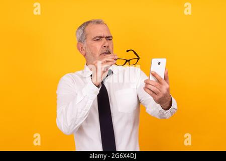 uomo adulto anziano isolato con presbiopia o vista della vista telefono Foto Stock