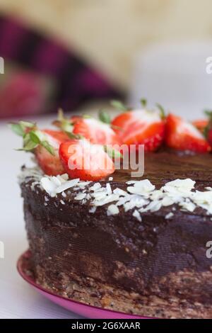 Torta al cioccolato con arachidi e fragole. Il processo di fare una torta. Primo piano. Foto Stock