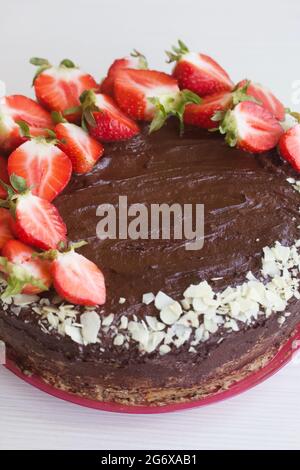 Torta al cioccolato con arachidi e fragole. Il processo di fare una torta. Primo piano. Foto Stock