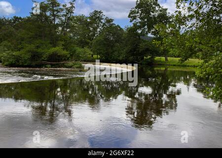 Weir sul fiume Dee a Llangollen, Galles, con il cielo e gli alberi riflessi in acqua Foto Stock