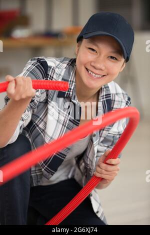 femmina costruttore che porta tubo rosso Foto Stock