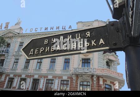 Odessa, Ucraina, 9 ottobre 2012: Un vecchio segno nero con il nome di Deribasovskaya Street a Odessa, Ucraina. Sullo sfondo dell'edificio dell'hotel Foto Stock