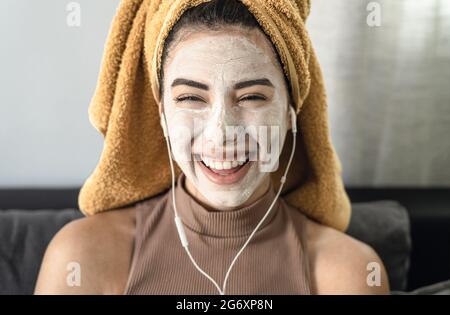 Giovane donna che ascolta musica mentre si ha cura della pelle spa giornata a casa Foto Stock