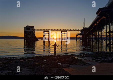 Nella foto: Natasha Jenkins in mare durante l'alba, visto attraverso la stazione delle barche RNLI a Mumbles, vicino a Swansea, Galles, Regno Unito. Domenica 13 Giugno 2021 Re: Foto Stock