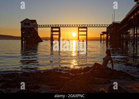 Nella foto: Natasha Jenkins in mare durante l'alba, visto attraverso la stazione delle barche RNLI a Mumbles, vicino a Swansea, Galles, Regno Unito. Domenica 13 Giugno 2021 Re: Foto Stock