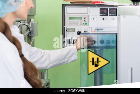 Primo piano della mano di un ingegnere di produzione femminile che regola le impostazioni di una macchina industriale durante il lavoro in una moderna fabbrica di cosmetici Foto Stock