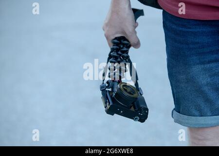 mano dell'uomo che tiene una macchina fotografica con un treppiede flessibile all'aperto Foto Stock