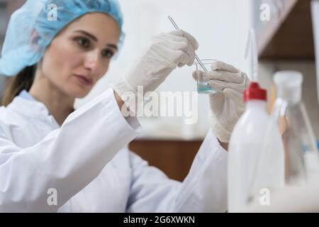 Donna chimica dedicata che crea una sostanza innovativa ed efficiente durante il lavoro in laboratorio, di una moderna fabbrica di cosmetici Foto Stock