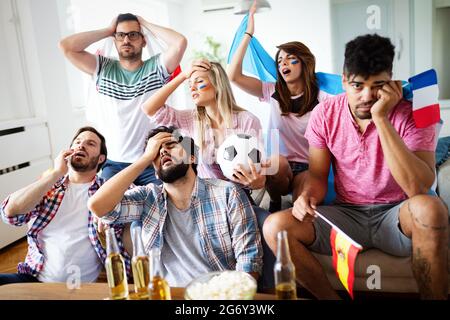 Amici sconvolti e frustrati che guardano la partita di calcio a casa Foto Stock