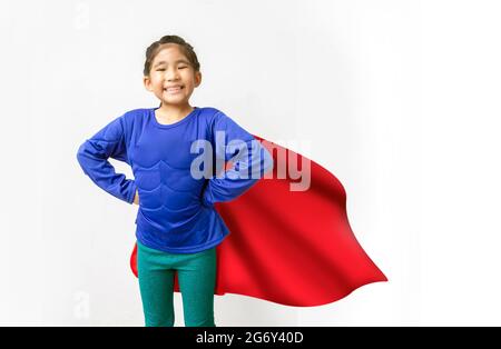 Little Asian bambino gioca supereroe. Ragazza sullo sfondo con concetto di supereroi in Girl Power Concept. Foto Stock