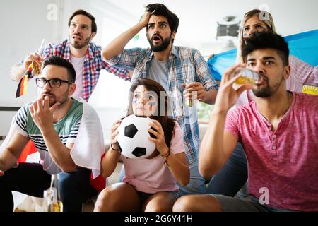 Gruppo di Tifosi delusi e felice di guardare una partita di calcio sul lettino. Foto Stock