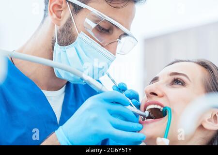 Vista laterale primo piano di una giovane donna rilassata durante un trattamento orale indolore nel moderno studio dentistico di un dentista esperto e dedicato Foto Stock