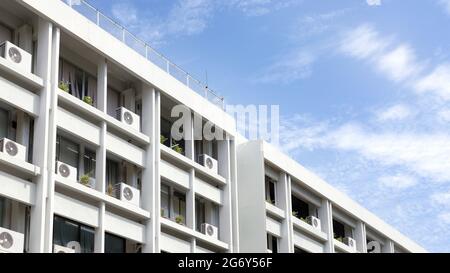Compressore d'aria parte del sistema di aria condizionata sul balcone con cespuglio di albero su edificio con sfondo cielo. Foto Stock