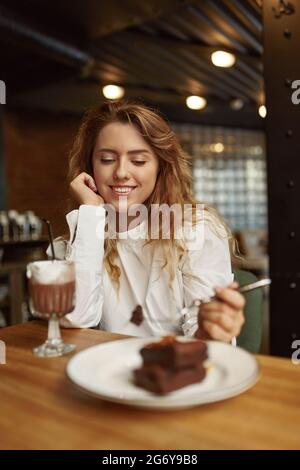 Donna che passa del tempo libero al caffè con torta e caffè Foto Stock
