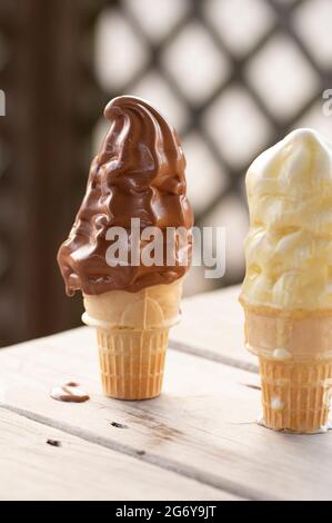 Coni gelato alla vaniglia e al cioccolato che si fondono nel caldo estivo Foto Stock