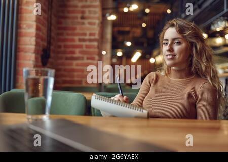Studente che guarda lo schermo del computer e prende appunti Foto Stock