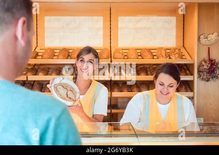 Due salesladies vendita di pane ed altri prodotti di panificio a lavorare come un team Foto Stock