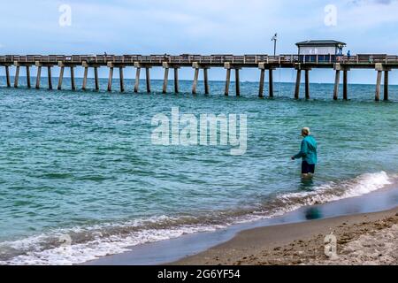 L'uomo entra nel surf accanto al molo di Venezia, Venice Beach, Florida. Foto Stock