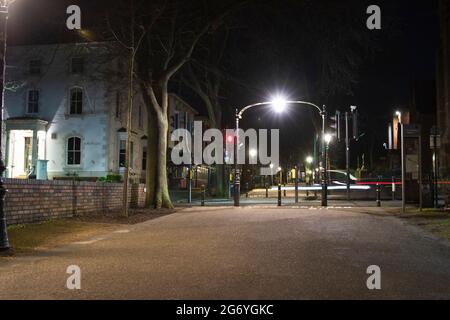 Foto notturna di New Walk guardando De Montfort Street che la attraversa. Auto sfocata che attraversa la strada. Luci da strada luminose. Foto Stock