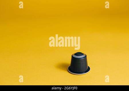 Una capsula di caffè isolata su sfondo giallo Foto Stock