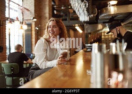 Donna sorridente che trascorre il tempo libero al bar con caffè Foto Stock