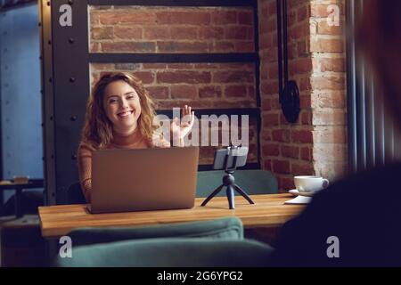 Donna sorridente e sventolante registrazione vlog su smartphone Foto Stock