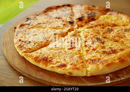 Closeup di Khachapuri Imeruli (Imeretian) appena sfornati o pane di flatbread georgiano farcito su piatto di legno Foto Stock