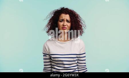 giovane donna sconvolto in camicia a manica lunga a righe isolata in blu Foto Stock