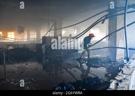 Narayanganj, Bangladesh. 09 luglio 2021. Un vigile del fuoco ispeziona la fabbrica Hashem Foods Ltd dopo lo scoppio di un incendio a Rupganj, distretto di Narayanganj, alla periferia di Dhaka. Almeno 52 persone sono state uccise, 25 altre ferite e molte sono temute intrappolate dopo un incendio massiccio infuriato in una fabbrica, la causa dell'incendio che ha avuto origine a un piano terra di un edificio a più piani della fabbrica non è ancora nota. Credit: SOPA Images Limited/Alamy Live News Foto Stock